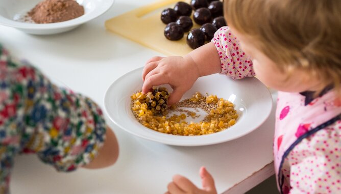 Backen mit Kindern | © SONNENTOR Auf dem Foto sieht man wie ein Kind Energieballs ummantelt. | © SONNENTOR